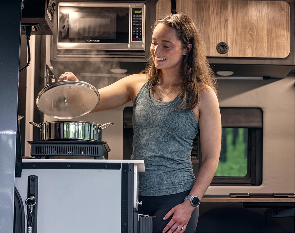 A woman cooking on the stove in her Tiffin motorhome